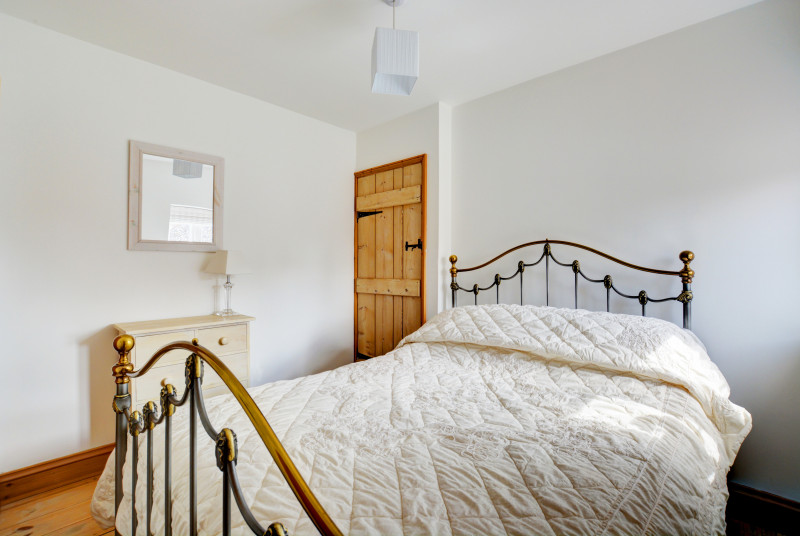 Pretty double bedroom with wrought iron double bed, feature fireplace and pine floorboards