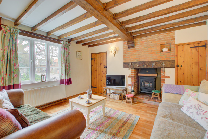The sitting room is a lovely cosy space with rustic open beams and an electric woodburner