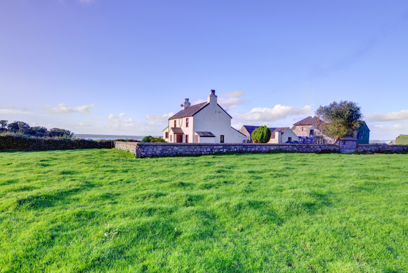 This farmhouse has farmyards and outbuildings to the rear, but faces open fields and distant sea views