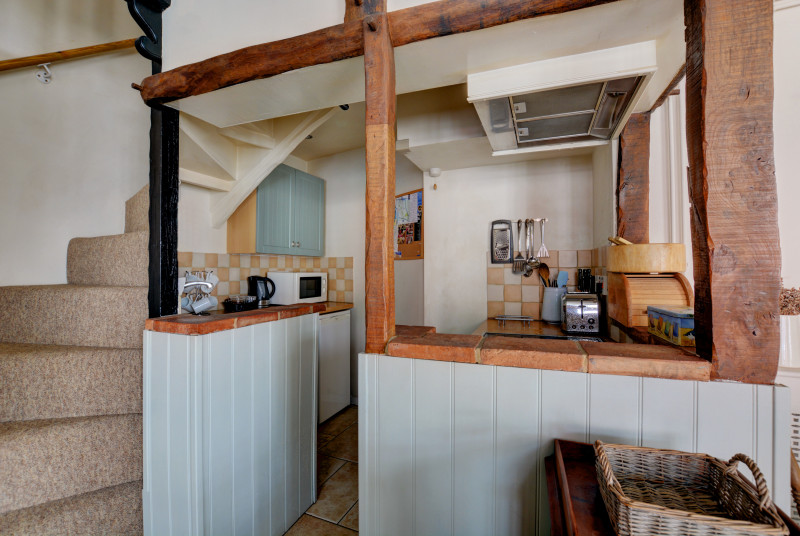 Compact kitchen with appliances situated at the bottom of the cottage style stairs.