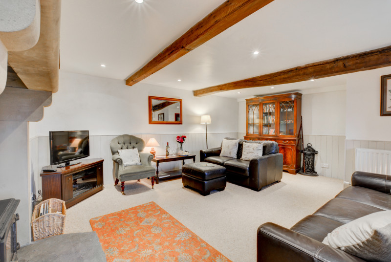 Spacious lounge with beamed ceiling and solid fuel stove