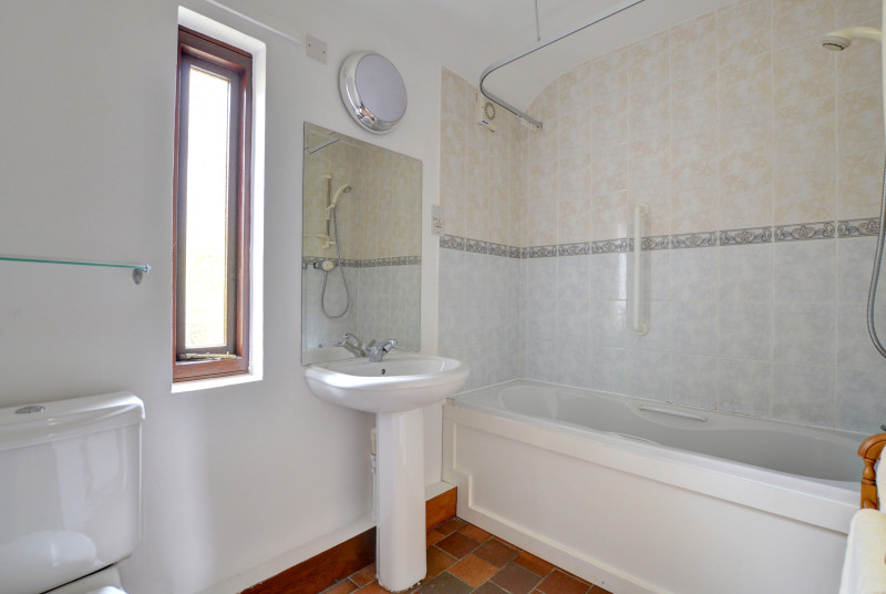 Bath shower room has shower over bath, sink and toilet