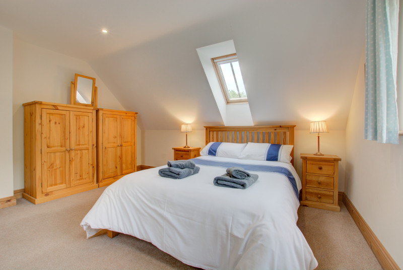 Good-sized room with double bed, bedside cabinets & cupboard, has sloping ceiling.