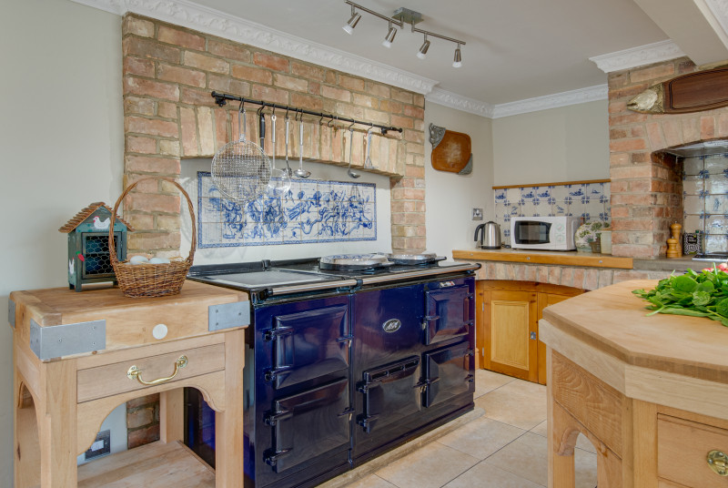 Kitchen with a large aga and hanging utensils