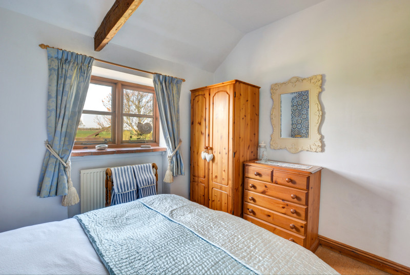 Characterful double bedroom with a wardrobe and chest of drawers for storage