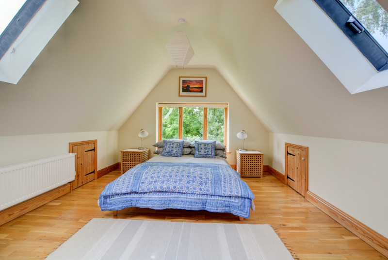The double bedroom has sloping ceiling and a large picture window.