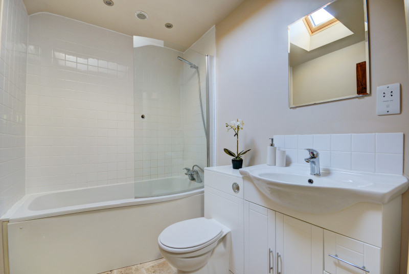 The ensuite off of bedroom one has a curved bath with an over bath shower, washbasin and wc