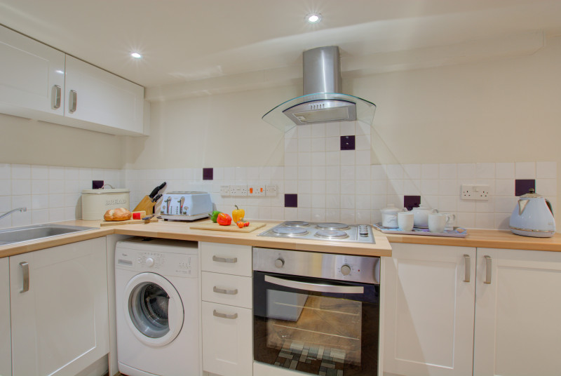 Modern fitted kitchen with  built-in electric oven, electric hob, fridge with icebox, microwave and washing machine 