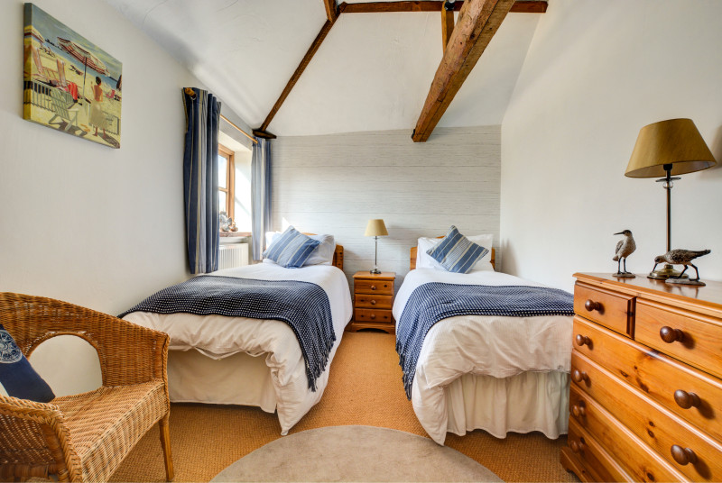Light and airy bedroom with twin beds and overhead beams