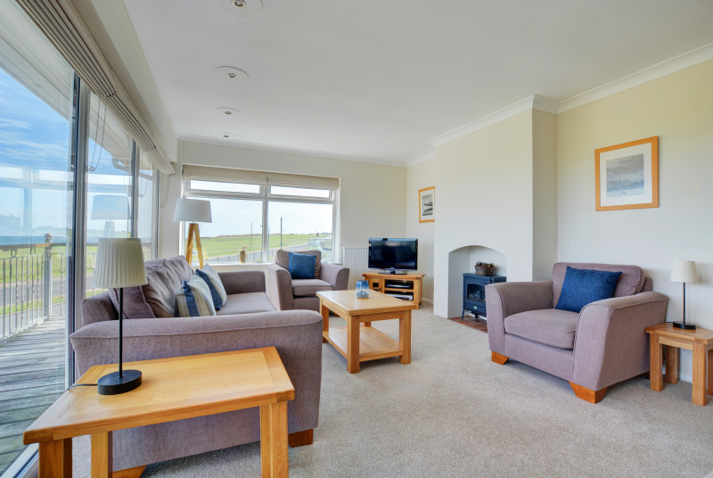 First floor pleasantly furnished with comfortable seating, electric woodburner-style fire and door to the balcony with splendid sea views