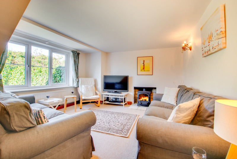 Sitting room with comfortable seating, TV and cosy woodburner