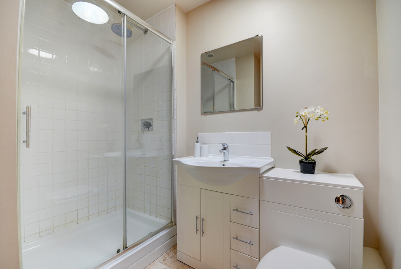 The fully tiled shower room has a large shower enclosure with a sliding glass door 