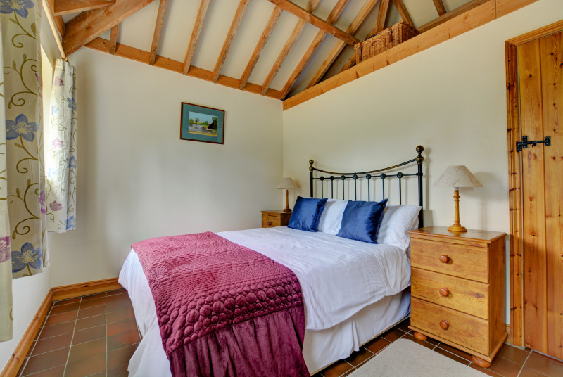 A double bedded room features an iron bedstead and pine furniture.