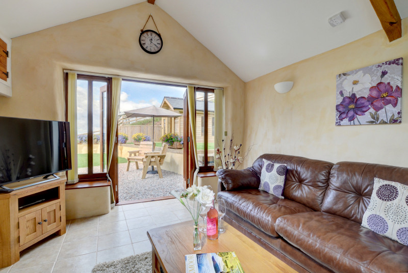 Comfortable seating and large TV in the seating area, with patio doors giving access to the garden