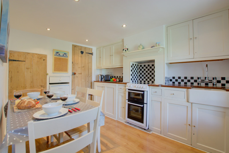 Kitchen with electric free-standing oven, electric induction hob, belfast sink, fridge with icebox, washer dryer, ining table with four chairs.d