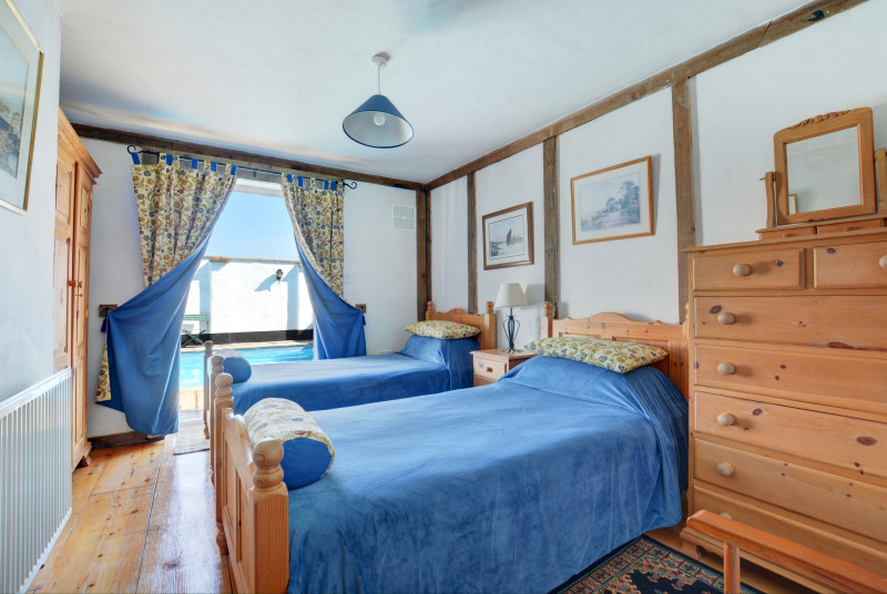 Traditional double bedroom with twin beds and patio doors leading to the swimming pool 