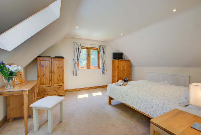 A large room with double bed, velux window and window to garden.