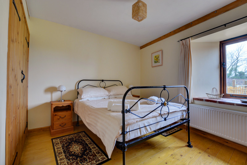 The second double bedroom with feature iron bed.  Wooden floors with cosy rugs beside the bed