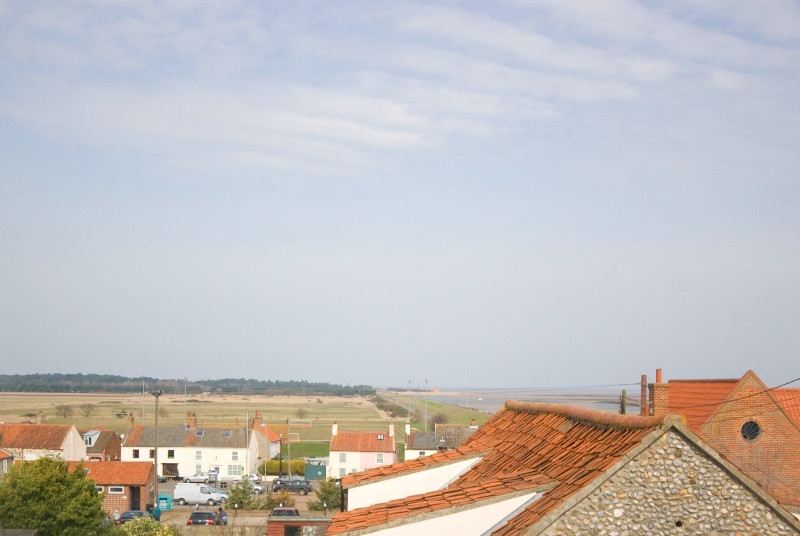 A view over the rooftops to the pinewoods and sea.
