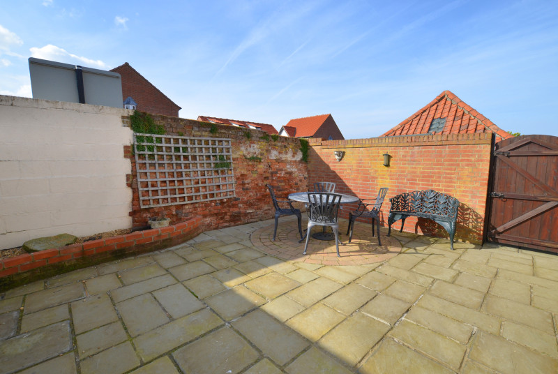 A walled patio garden with garden furniture and barbecue for dining alfresco