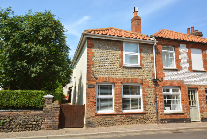Exterior image of this charming brick and flint cottage