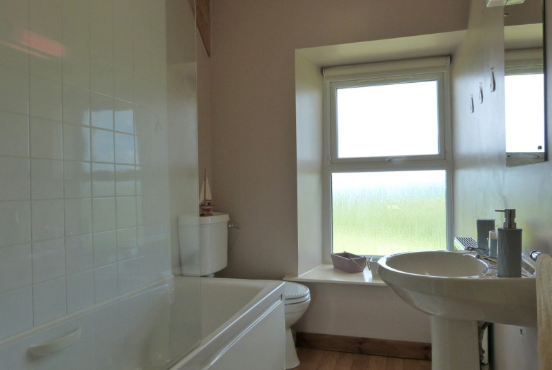 Bathroom with bath and electric shower above, washbasin and toilet
