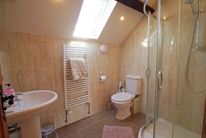 Fully tiled upstairs shower room with heated towel rail, WC and basin.