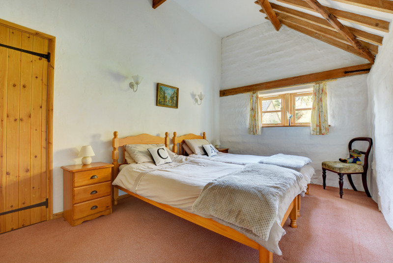 Bedroom 3 has twin beds and there are exposed beams on the ceiling