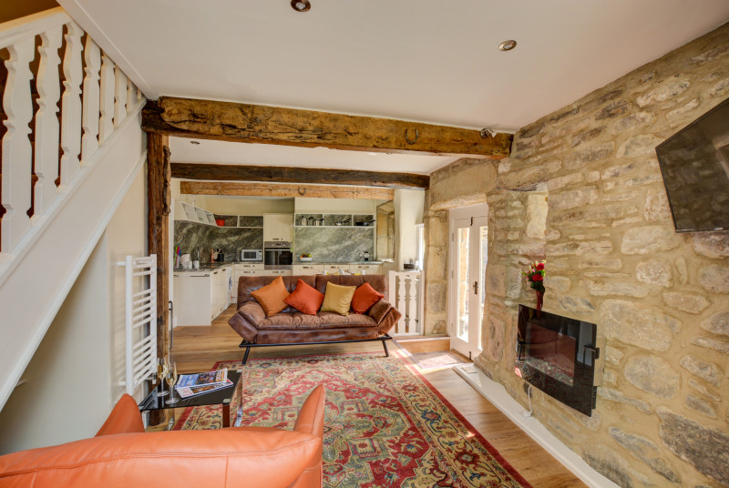 Open plan living area, with exposed stone walls, comfortable seating and well equipped kitchen