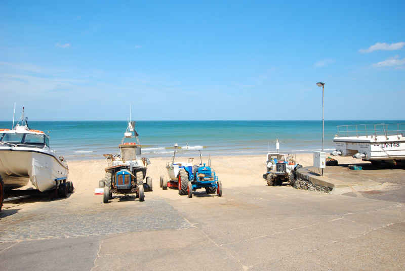 Boats and tractors lined up on the beach.