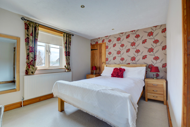 Double bed, pretty floral wall paper and matching curtains.