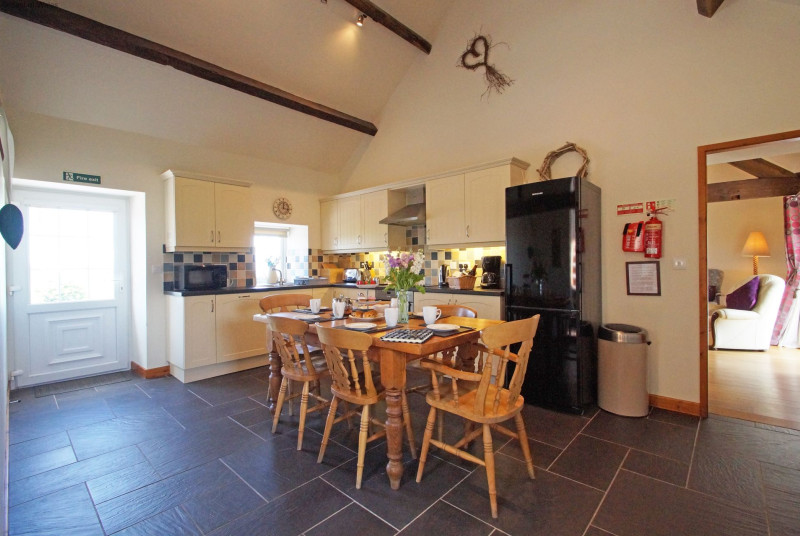 A spacious, cream 'shaker' style kitchen with a farmhouse pine table.