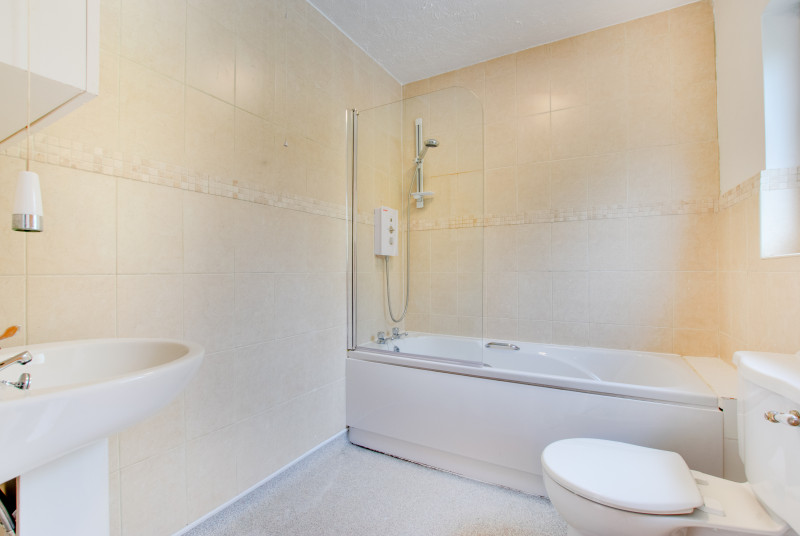 Large family bathroom, bath with shower over, toilet and wash basin.