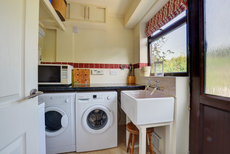 Utility room with washing machine, tumble dryer and sink