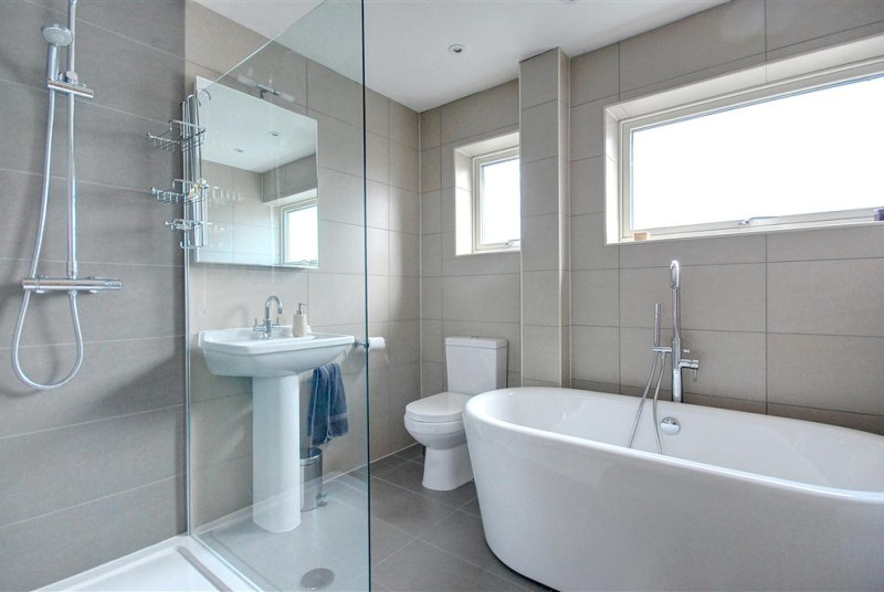 This modern fresh bathroom with roll top bath and biscuit coloured tiles is sure to help you relax.