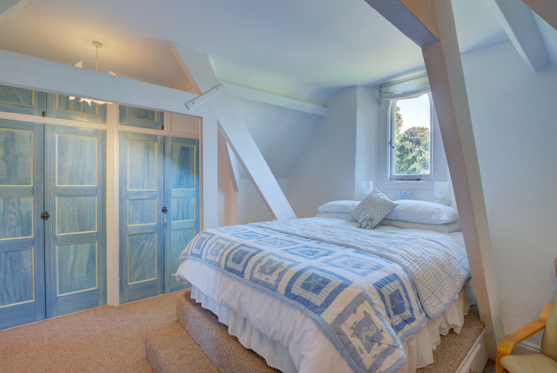 Bedroom One is furnished with a raised double bed, built in wardrobes and a chest of drawers.  There is a sloping ceiling and exposed beams.  A gothic window offers countryside views.