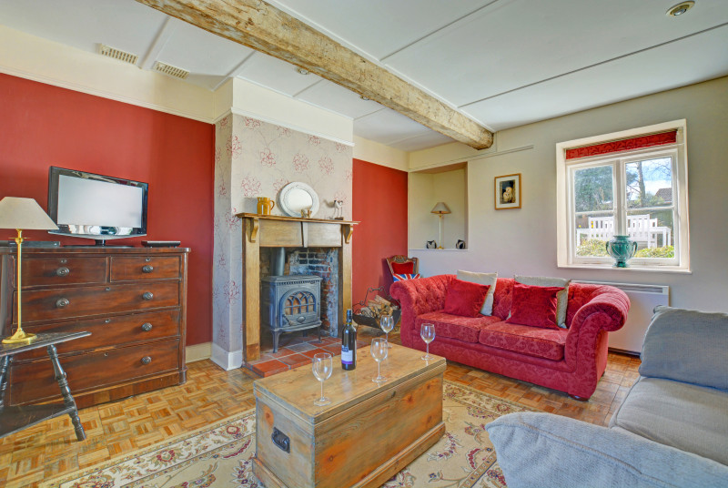 Spacious sitting room with comfortable seating and a traditional woodburner