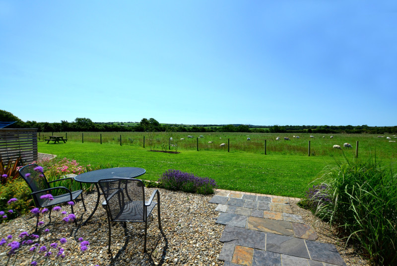 Small patio area to the rear of the cottage with garden furniture and views across farmland