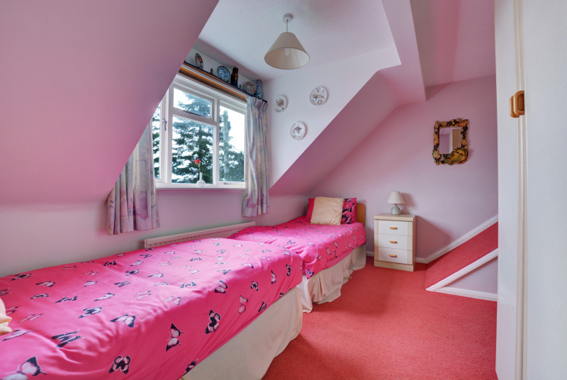 Twin bedroom with sloping ceilings and large window, ideal for children