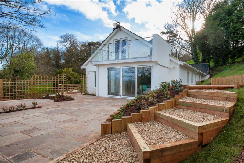 A sunny landscaped garden with a mix of lawned and terraced levels, perfect for alfresco dining